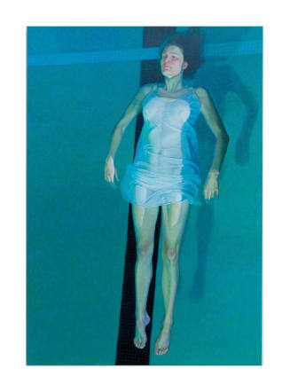 A person gazing upwards while floating in pool wearing a thin, white dress