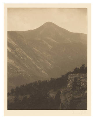 Greyscale photograph of a mountain with a stone structure in the lower right