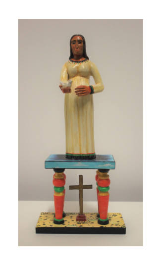 Figurine of a person holding a dove on a platform suspended above a cross